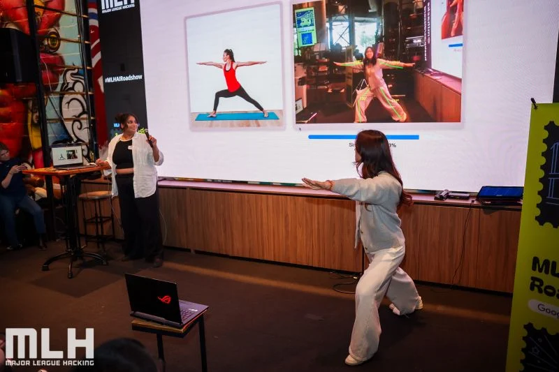 A presenter holds a yoga pose on stage while the projected ZenPose screen shows the reference pose and live camera feed